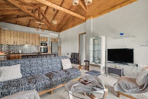 A modern living room with a wooden ceiling, a sofa, a television, and a glass cabinet. - Sia House Country Home with Sea View, Wi-Fi, and Air Conditioning (Ζαχάρω)