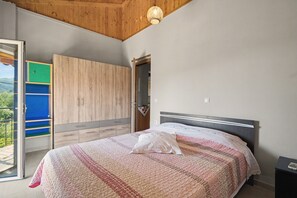 A bedroom with a bed, a wardrobe, and a balcony. - Sia House Country Home with Sea View, Wi-Fi, and Air Conditioning (Ζαχάρω)