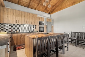 A modern kitchen with wooden cabinets, a checkered backsplash, and a central island with seating. - Sia House Country Home with Sea View, Wi-Fi, and Air Conditioning (Ζαχάρω)