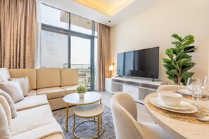 Ein modernes Wohnzimmer mit Sofa, Couchtisch, Fernseher und einem Essbereich, der für eine Mahlzeit gedeckt ist.
