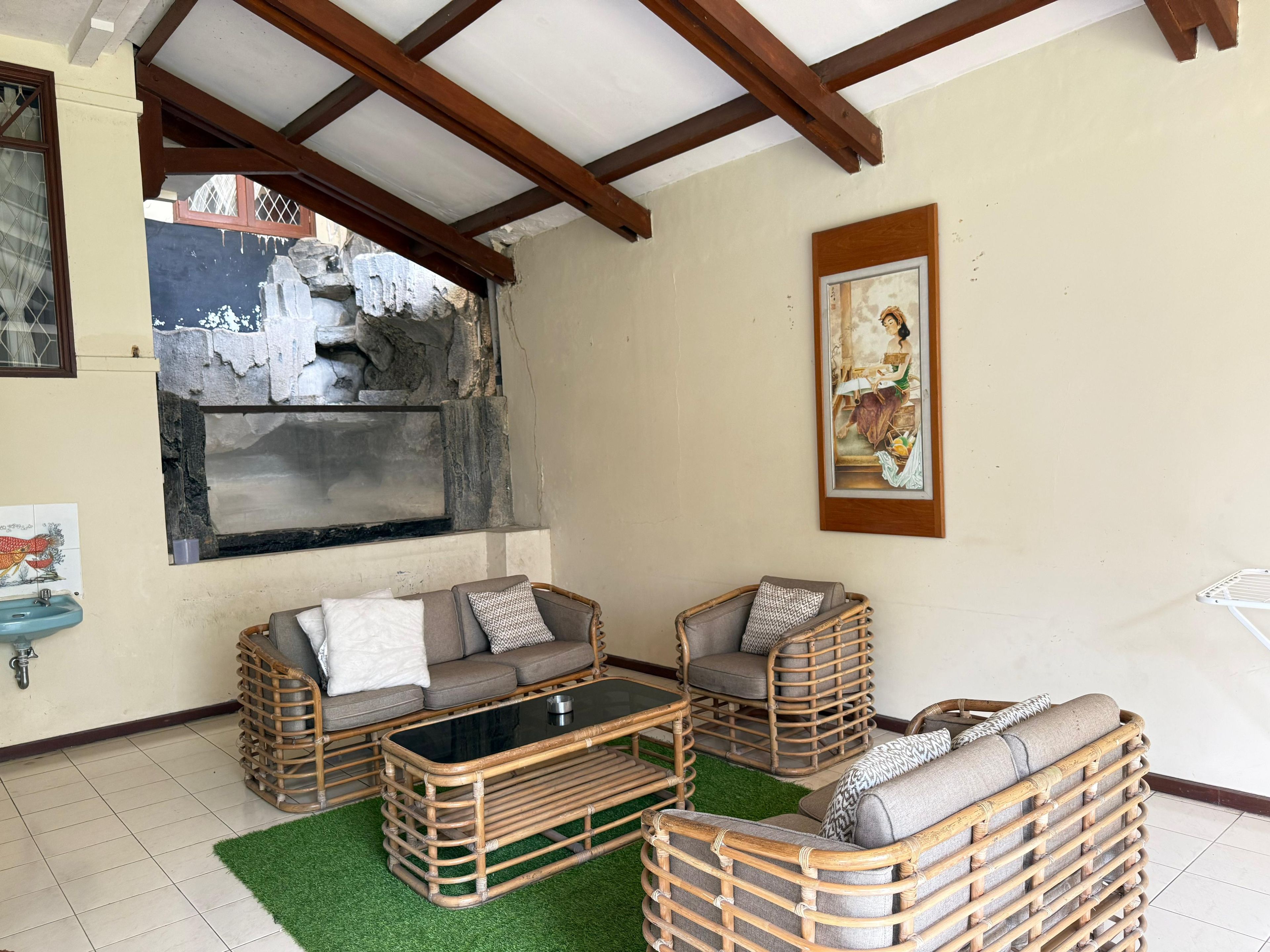 A room with a stone wall, a wooden ceiling, a sofa set, a table, and a painting.