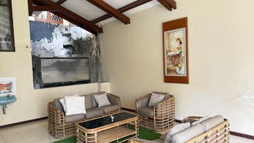 A room with a stone wall, a wooden ceiling, a sofa set, a table, and a painting.