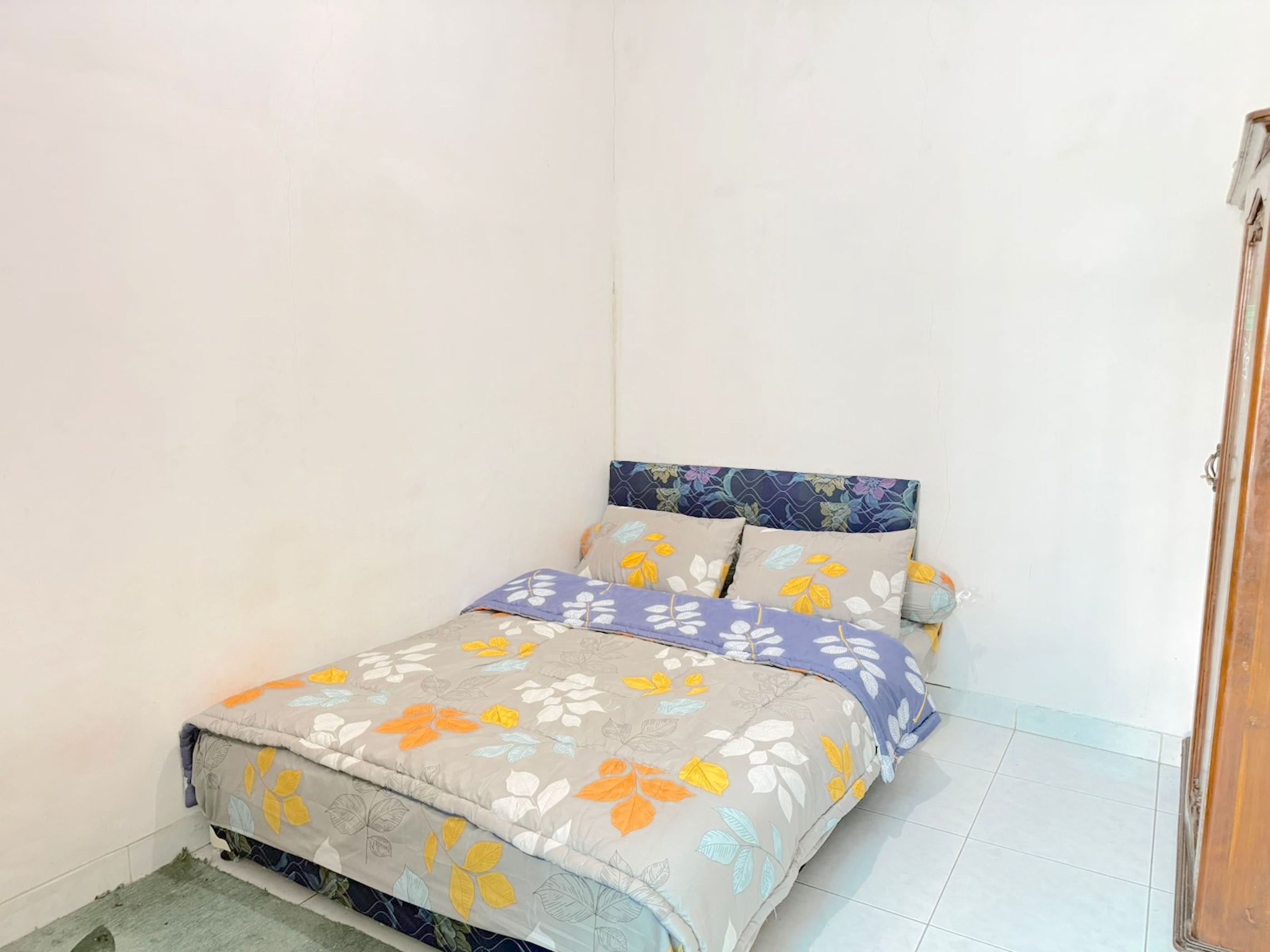 Una habitación pequeña con una cama individual, un edredón estampado con motivos florales y almohadas a juego.