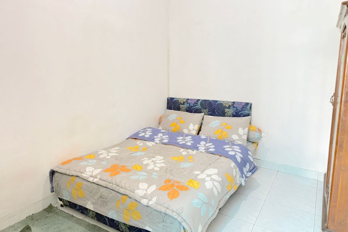 A small, single-bed room with a floral-patterned bedspread and matching pillows.