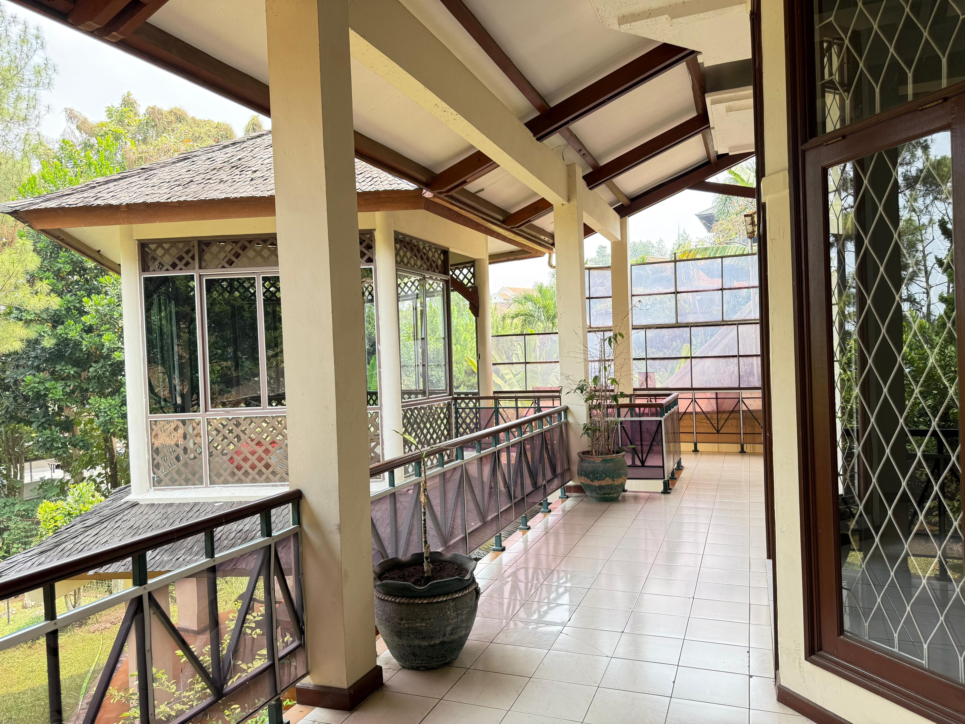 A covered outdoor area with a tiled floor, a railing, and a potted plant.