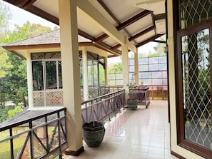 A covered outdoor area with a tiled floor, a railing, and a potted plant. - Kuca Plava (Cimenyan)