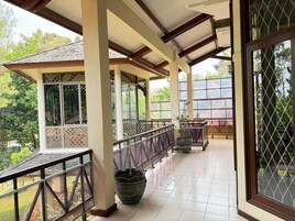 A covered outdoor area with a tiled floor, a railing, and a potted plant.
