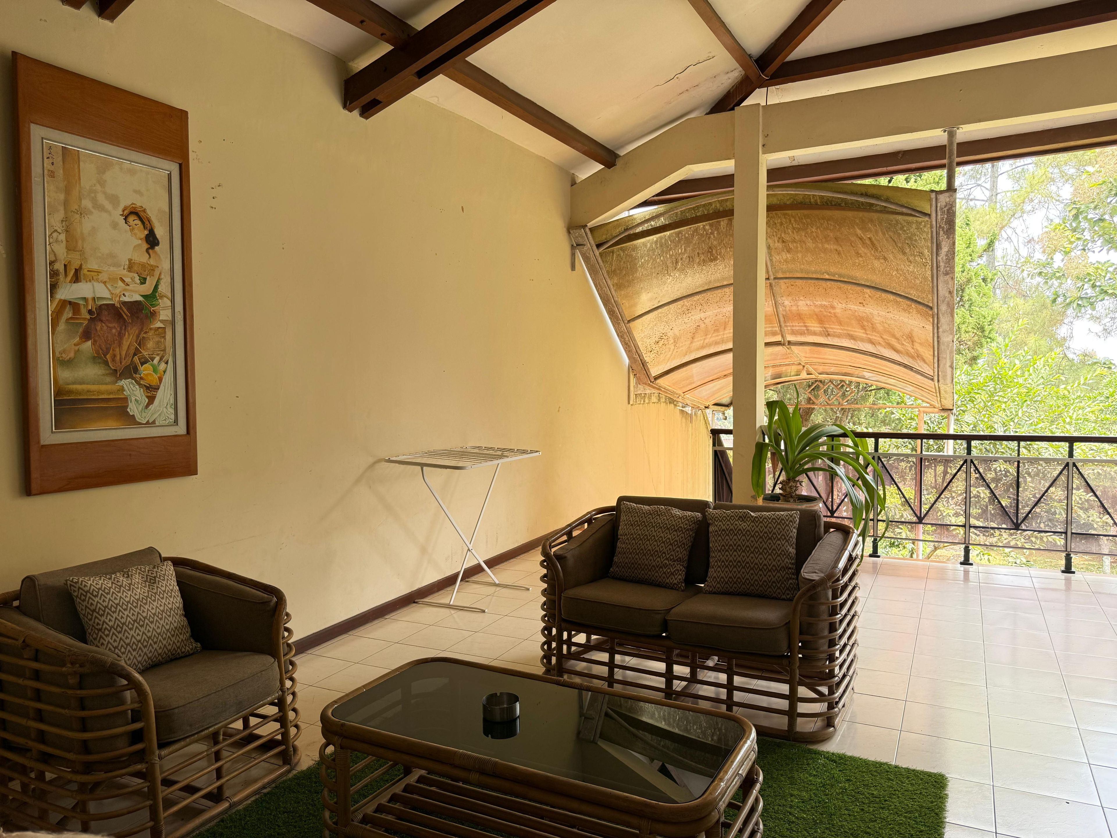 A room with wicker furniture, a glass coffee table, and a painting on the wall.