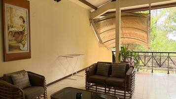 A room with wicker furniture, a glass coffee table, and a painting on the wall.