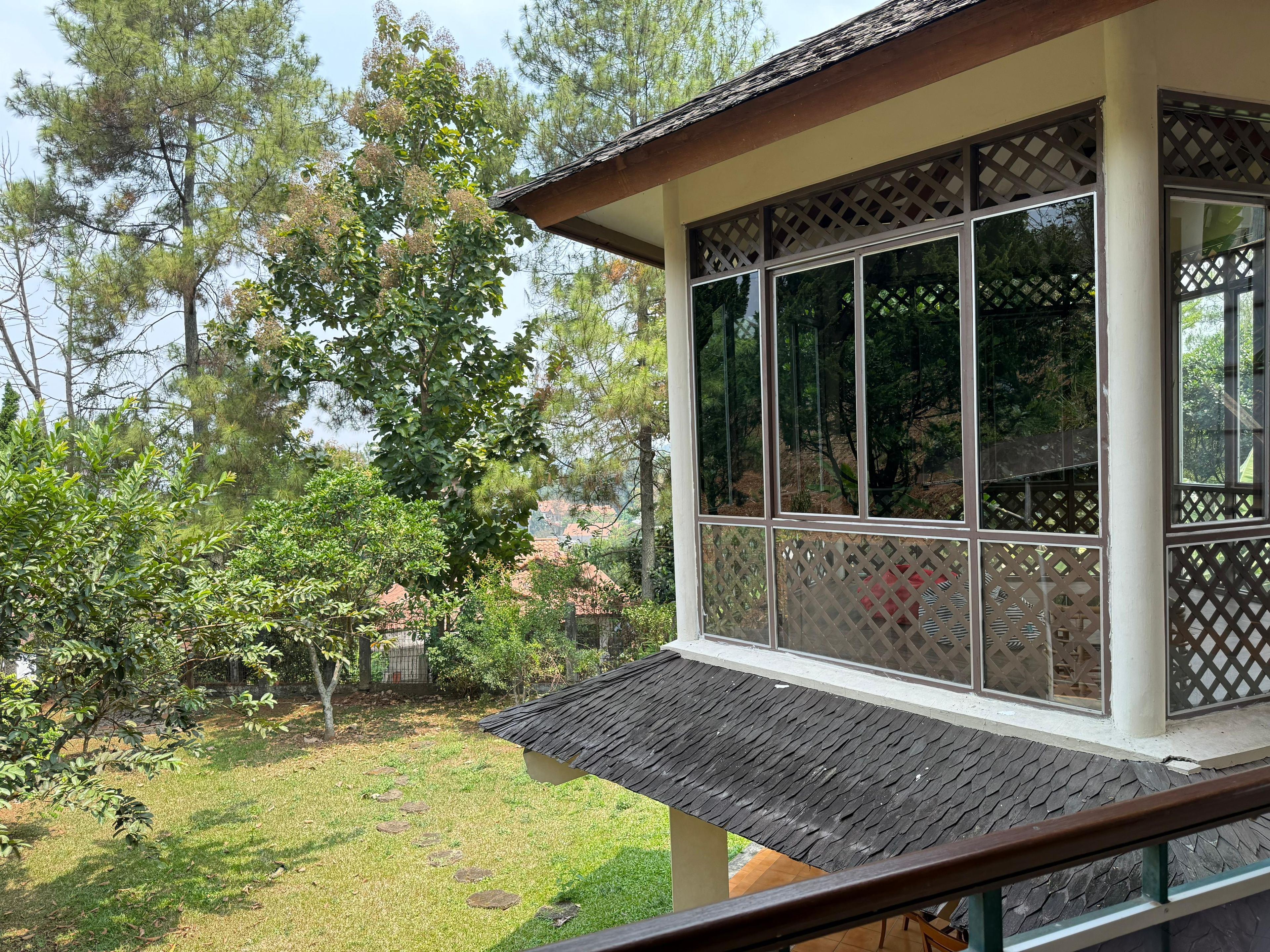 Un espace extérieur abrité offrant une vue sur un jardin et des arbres.