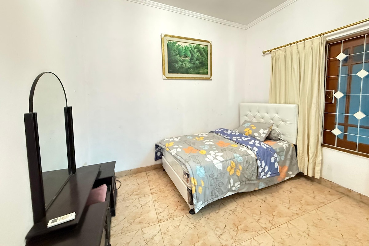 A bedroom with a bed, a dresser, a mirror, a window with curtains, and a framed picture on the wall.