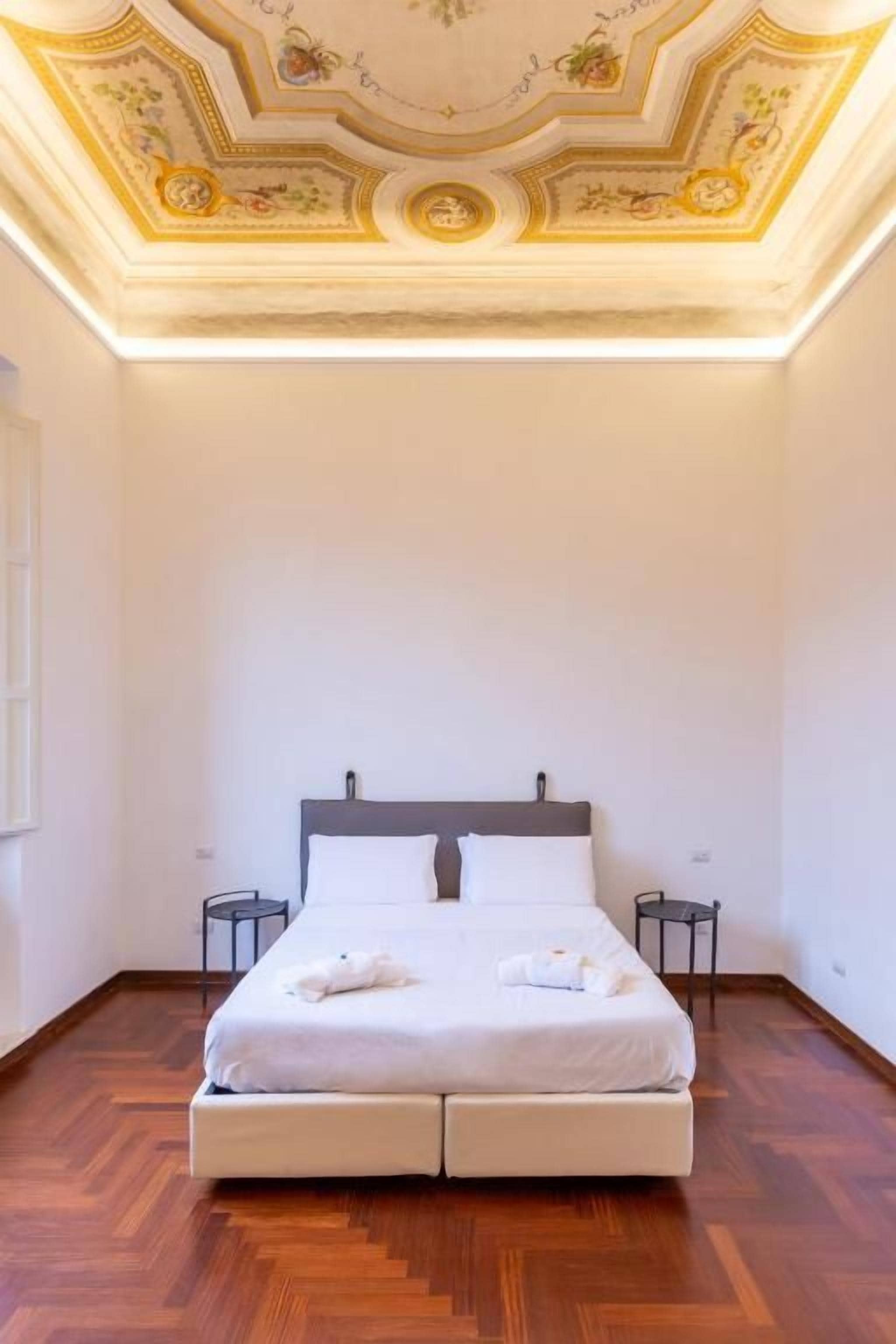 A single bed with a wooden headboard in a room with a wooden floor and a decorative ceiling.