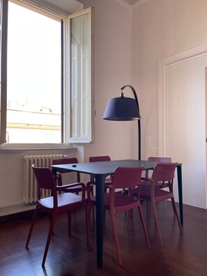 A dining area with a table and chairs, a radiator, and a window with curtains. - Luciano Monti Apartment (Roma)