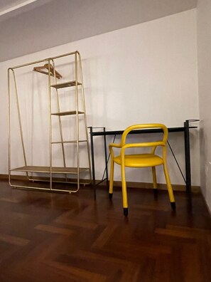 A room with a wooden floor, a yellow chair, and a metal shelf unit. - Luciano Monti Apartment (Roma)