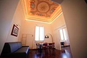 A room with a dining table, chairs, a sofa, and a ceiling with intricate designs. - Luciano Monti Apartment (Roma)