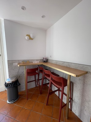 A kitchen with a marble backsplash, a wooden countertop, and red bar stools. - Luciano Monti Apartment (Roma)