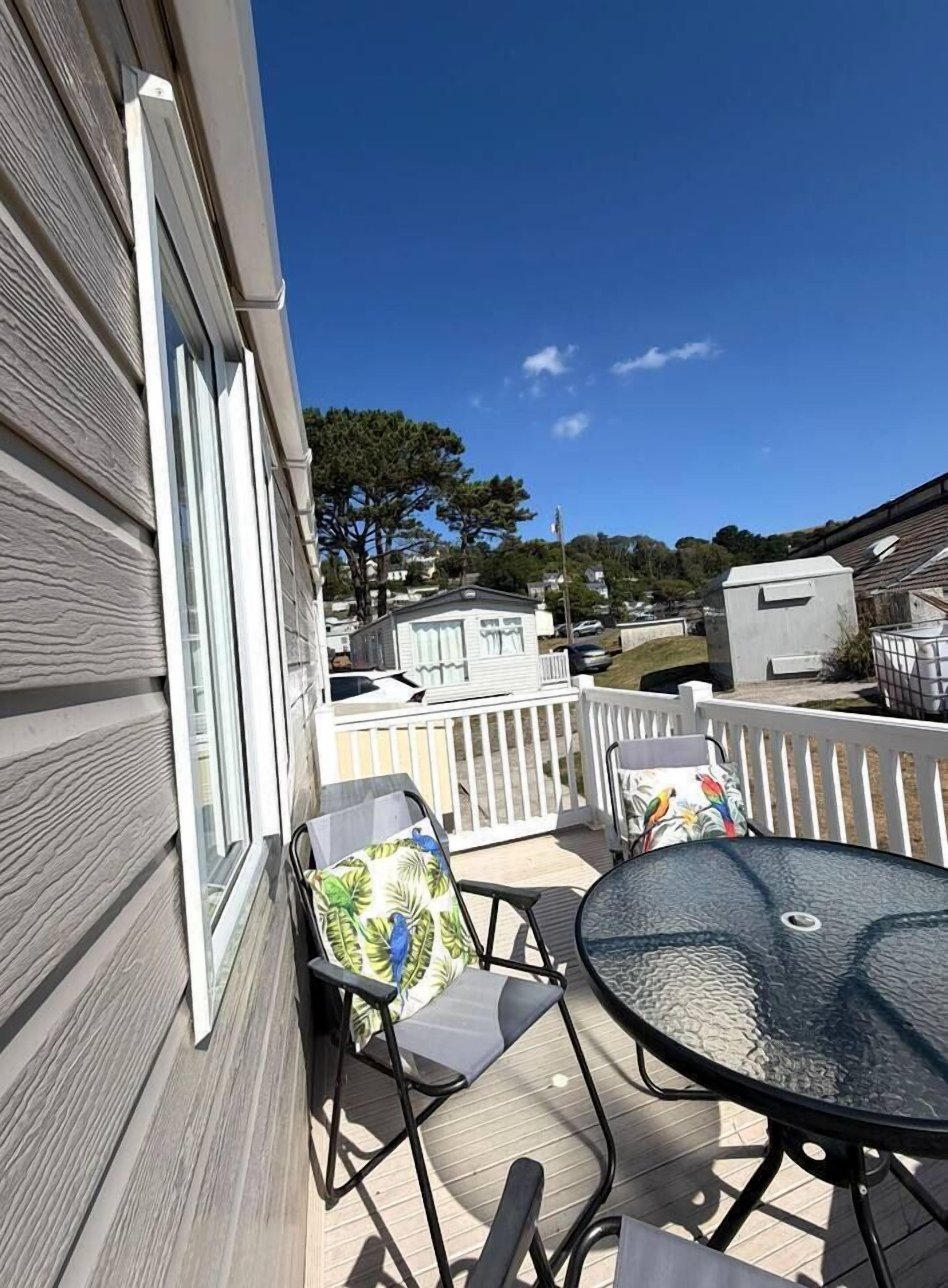 A patio with a round table and two chairs, a white railing, and a view of neighboring houses.
