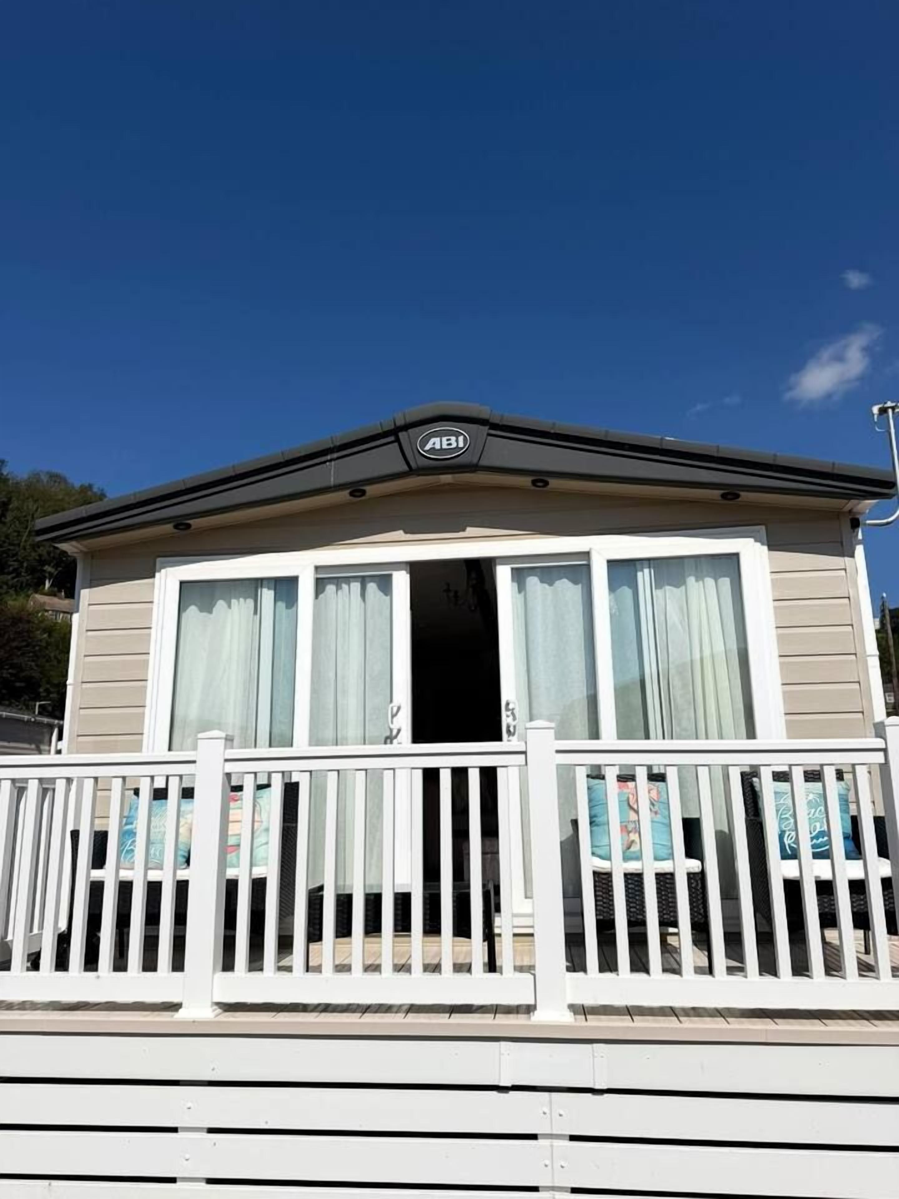 A mobile home with a balcony, a window with curtains, and a sign above the door.