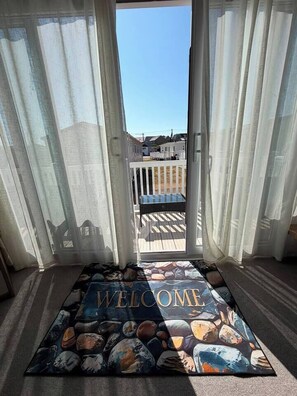 A room with a view of a deck and a 'WELCOME' mat with a geological theme.