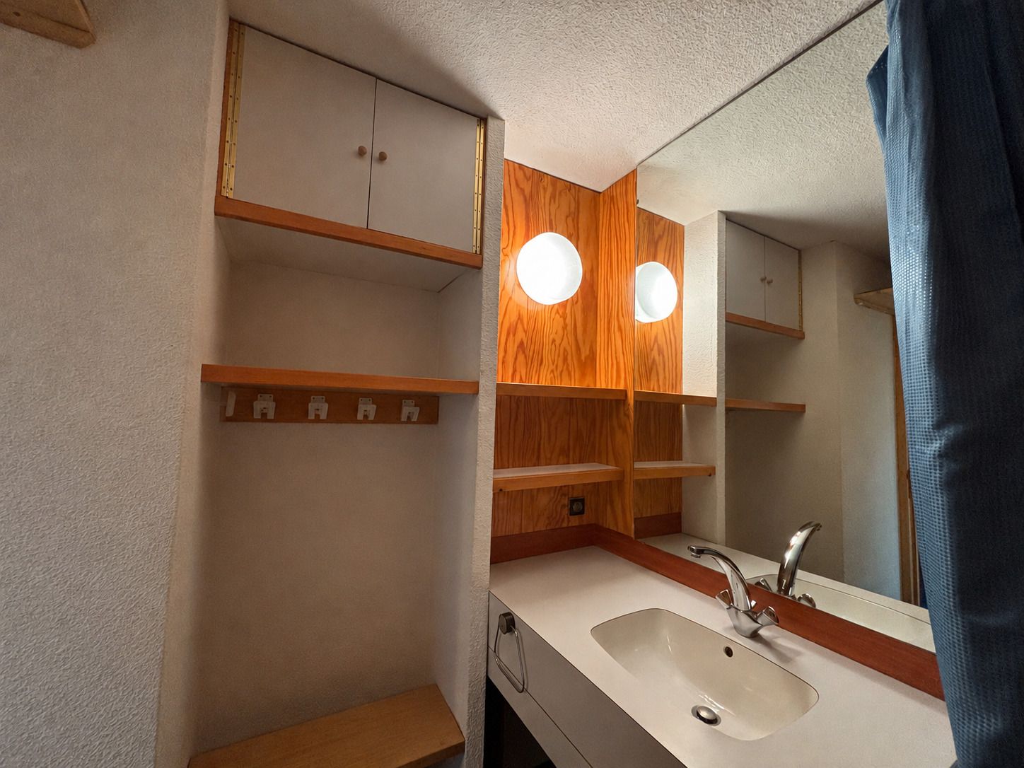 Een badkamer met een witte wastafel, houten kastjes en een spiegel met verlichting.