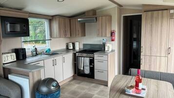 A compact kitchen with a microwave, toaster, sink, stove, and cabinets.