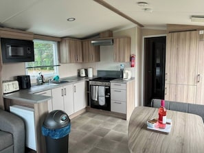 A compact kitchen with a microwave, toaster, sink, stove, and cabinets.