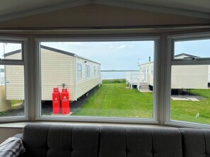 A view from inside a mobile home with a window overlooking a grassy area and other mobile homes.