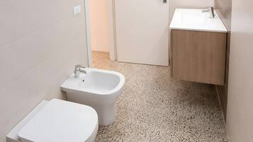 Un bagno con un WC, un bidet e un lavandino.