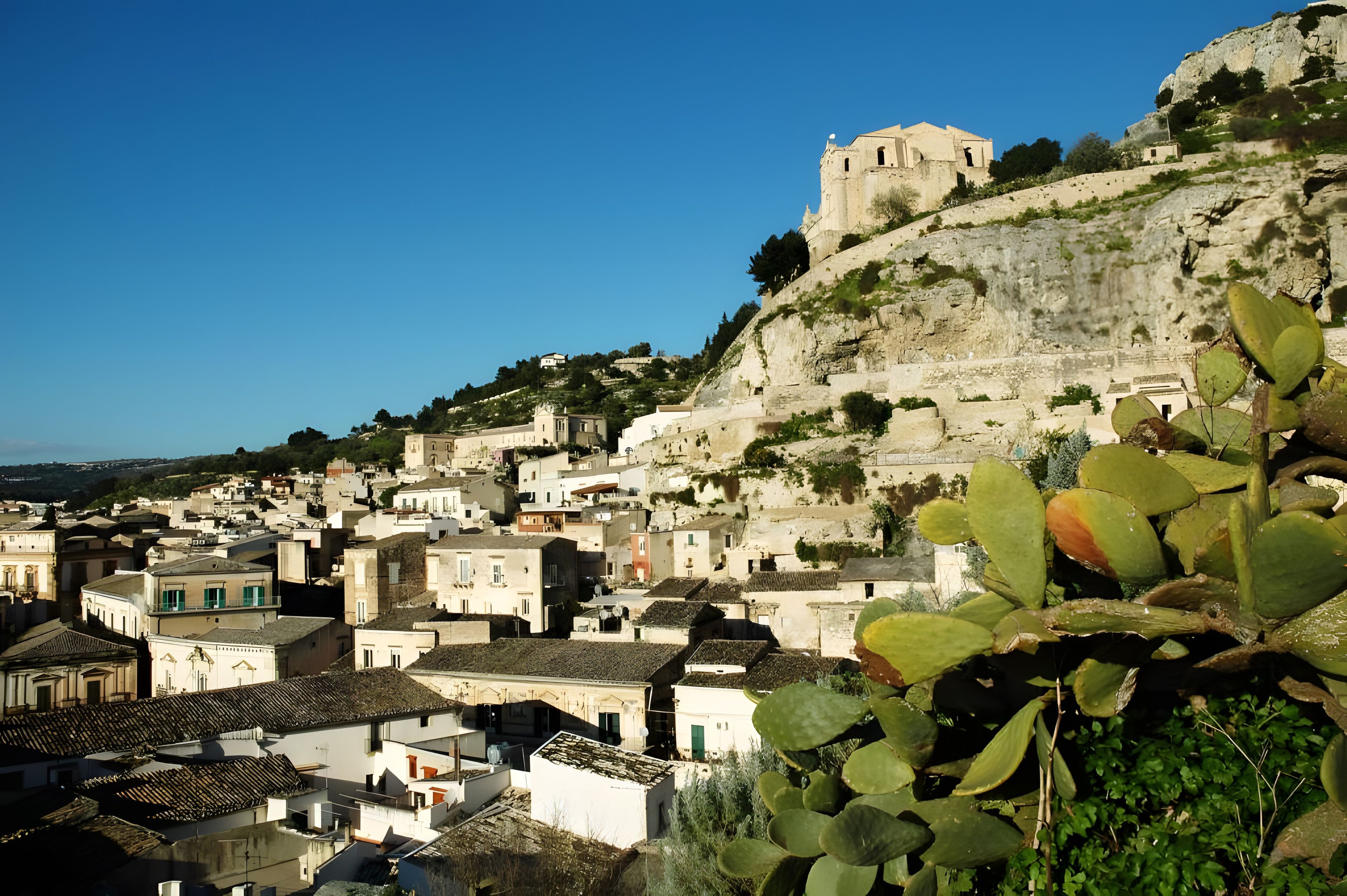 A coastal town with historic buildings, a prominent church, and a castle on a hill.