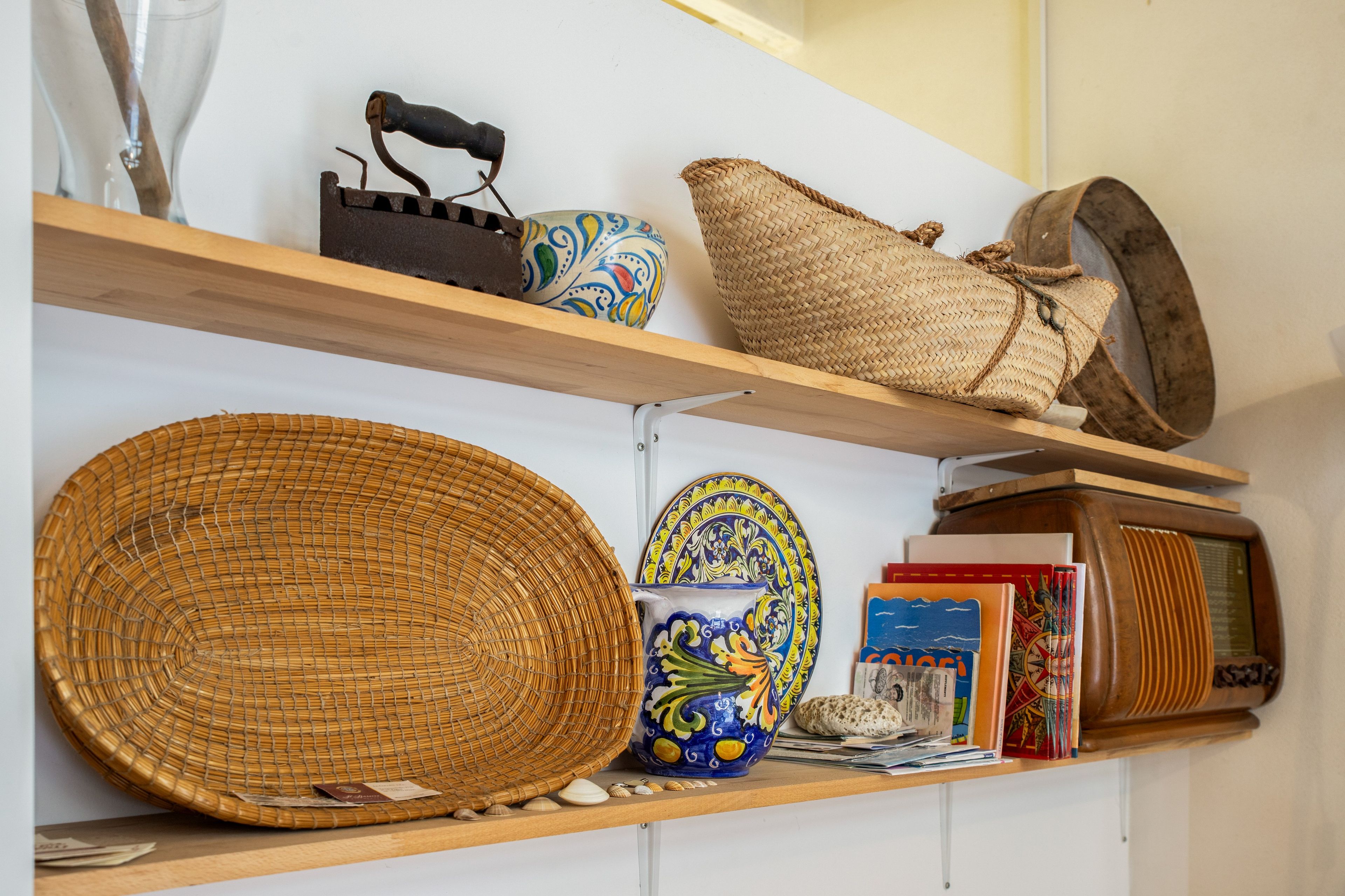 A shelf with woven baskets, a ceramic pot, and a radio.