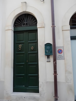 Une porte à deux battants, peinte en vert, avec le numéro « 40 » au-dessus, une boîte aux lettres et un panneau indiquant qu’il est interdit de se garer.