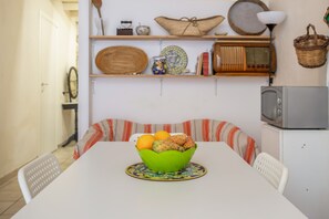 Un tavolo da pranzo con una ciotola verde di frutta e un sottopiatti decorato.