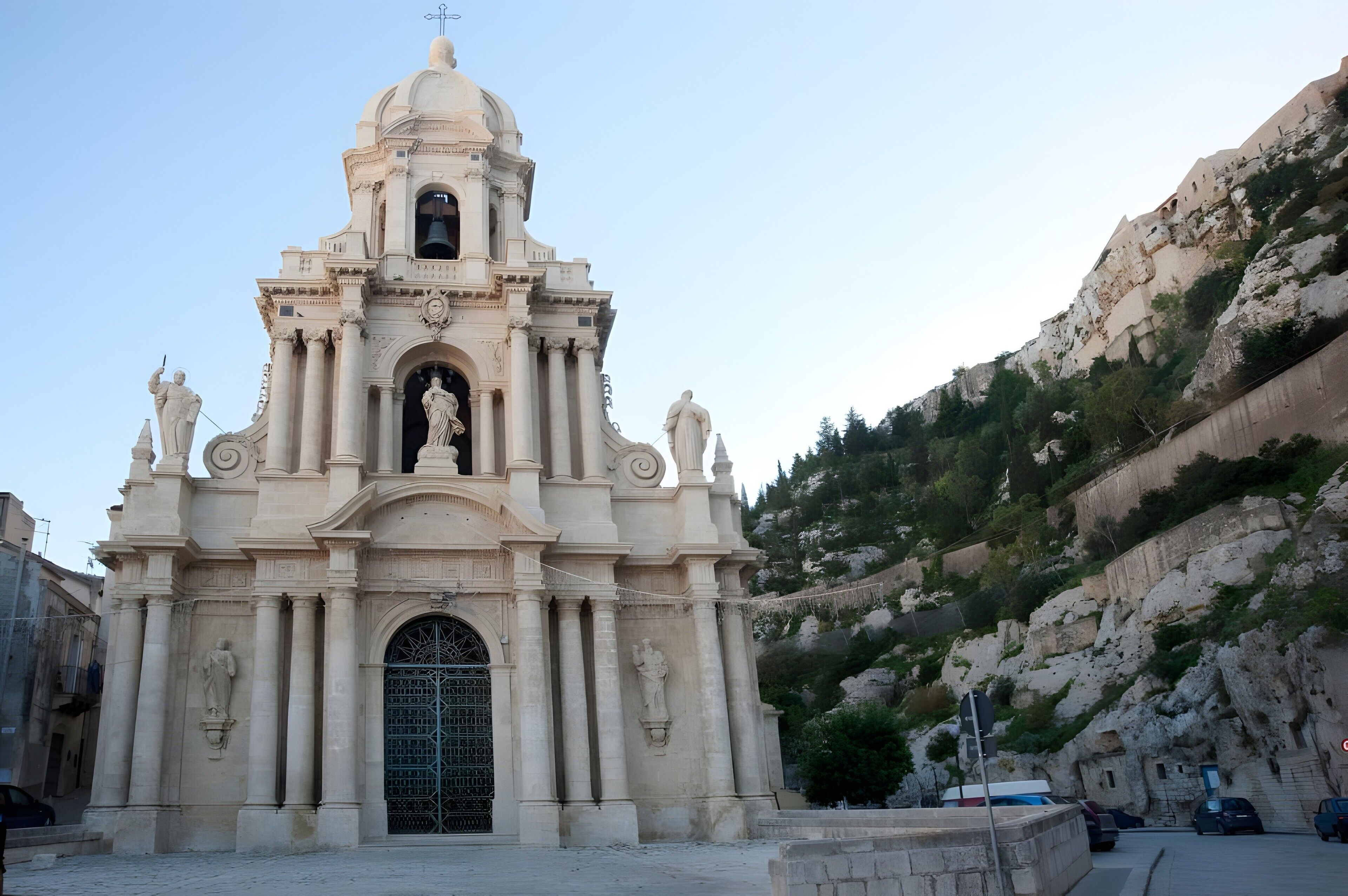 A historic church with a bell tower, arched entrance, and statues.