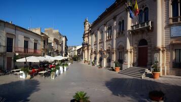 A square with outdoor seating, a building with classical architecture, and a flag.