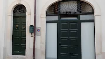 A building with two green doors, a no parking sign, and a mailbox.