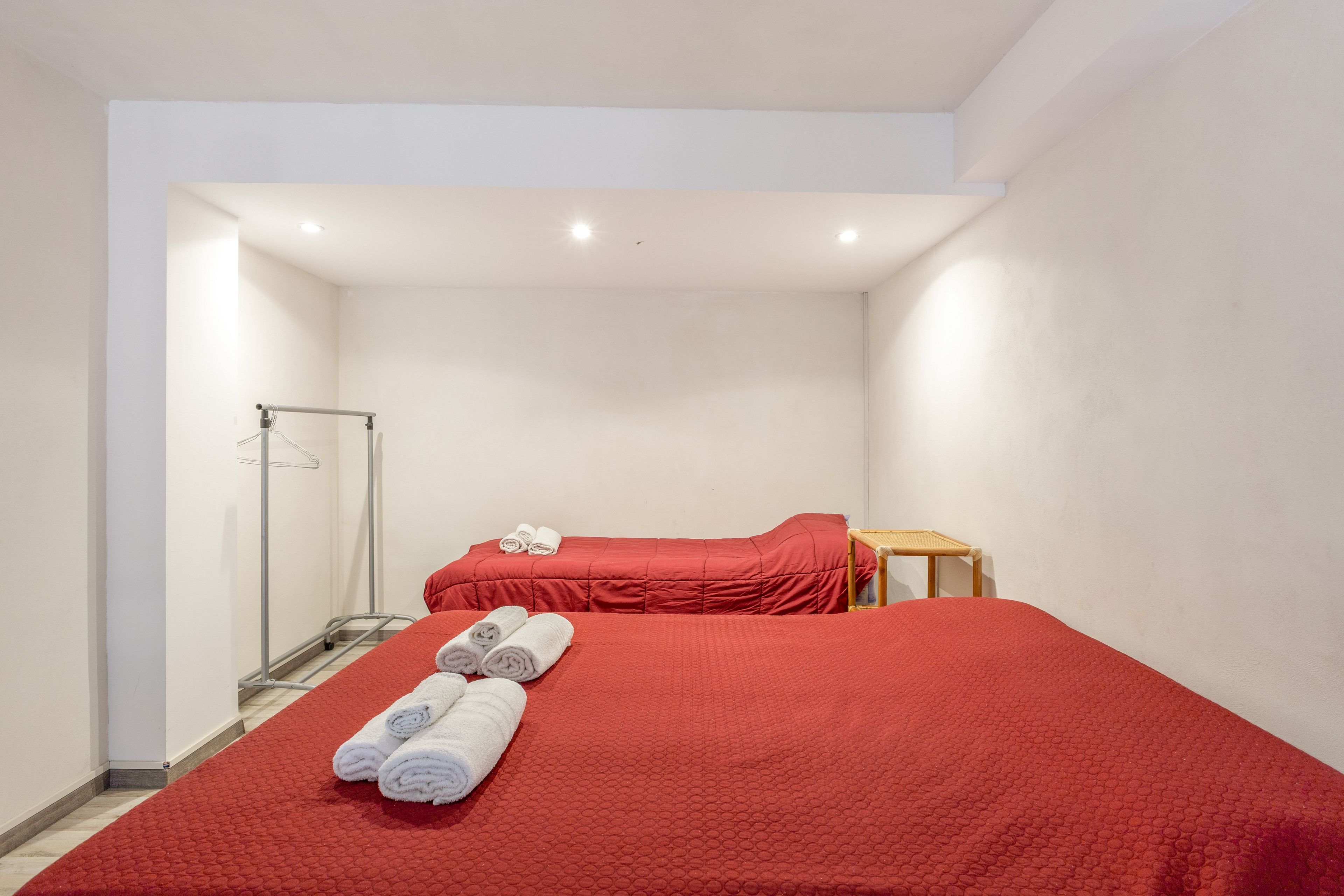 A hotel room with two beds, a shower area, and a wooden chair.