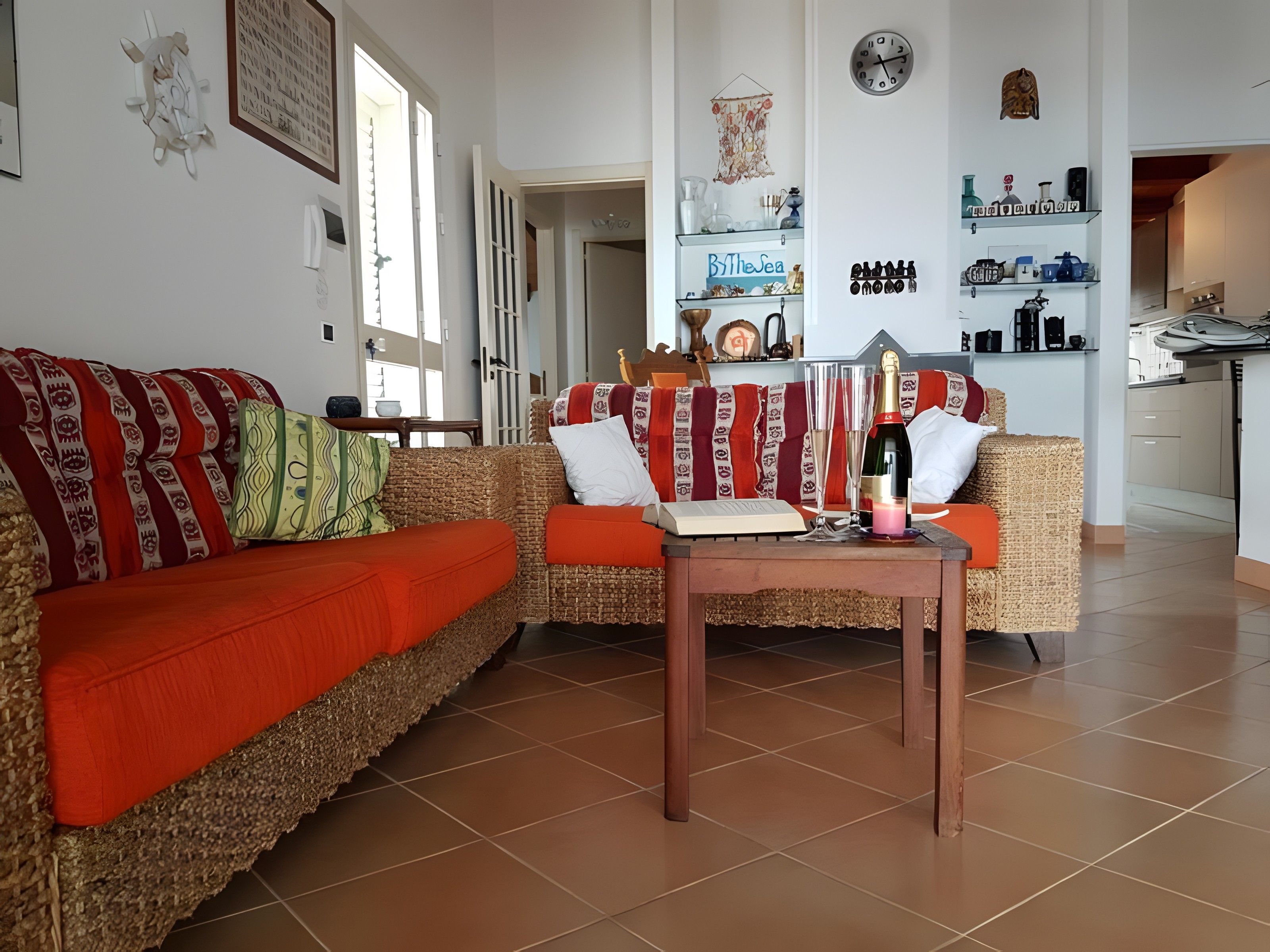 Un soggiorno con un divano, un tavolo con una bottiglia e una parete con una sveglia e decorazioni.