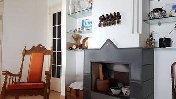 Una sala de estar con chimenea, una mecedora de madera y estantes con objetos decorativos.