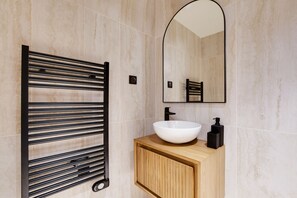 A bathroom with a white sink, a black towel rack, and a mirror. - Two-Bedroom Apartment (Paris)