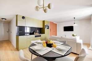A modern kitchen with a dining area, a flat-screen TV, and a sofa. - Two-Bedroom Apartment (Paris)