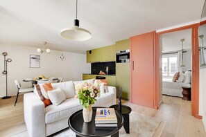 A modern living room with a sofa, coffee table, and a dining area. - Two-Bedroom Apartment (Paris)