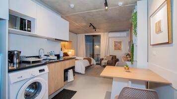 Une chambre d’hôtel compacte comprenant un coin cuisine, un lit, un espace salon et une petite table.