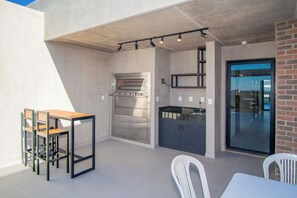 A modern kitchen with a built-in oven and a dining area with a table and chairs. - Corporate Stays First del Sol - 106 (Asunción)
