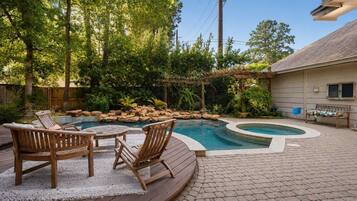 A backyard with a swimming pool, wooden deck, and outdoor furniture.