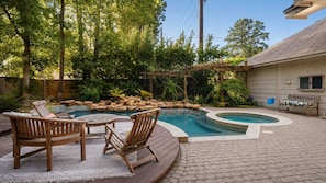 Un jardin avec une piscine, une terrasse en bois et du mobilier d’extérieur.