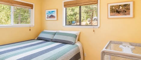 Une chambre à coucher avec un lit, deux fenêtres et un berceau.