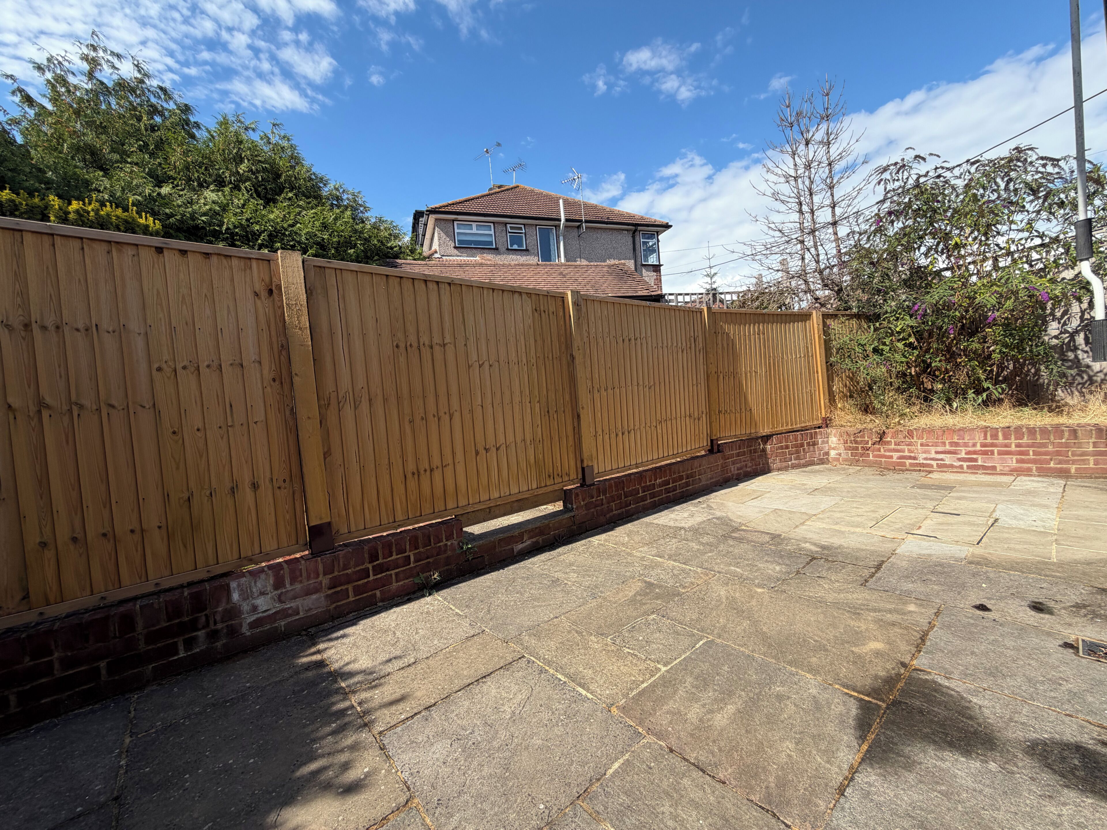 A fenced backyard with a house in the background.