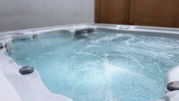 A hot tub with water, surrounded by a wooden fence.