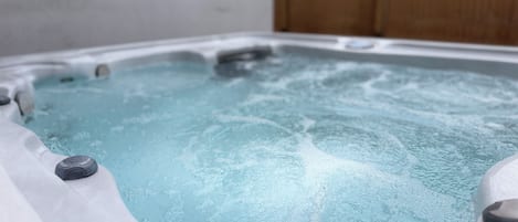 A hot tub with water, surrounded by a wooden fence.