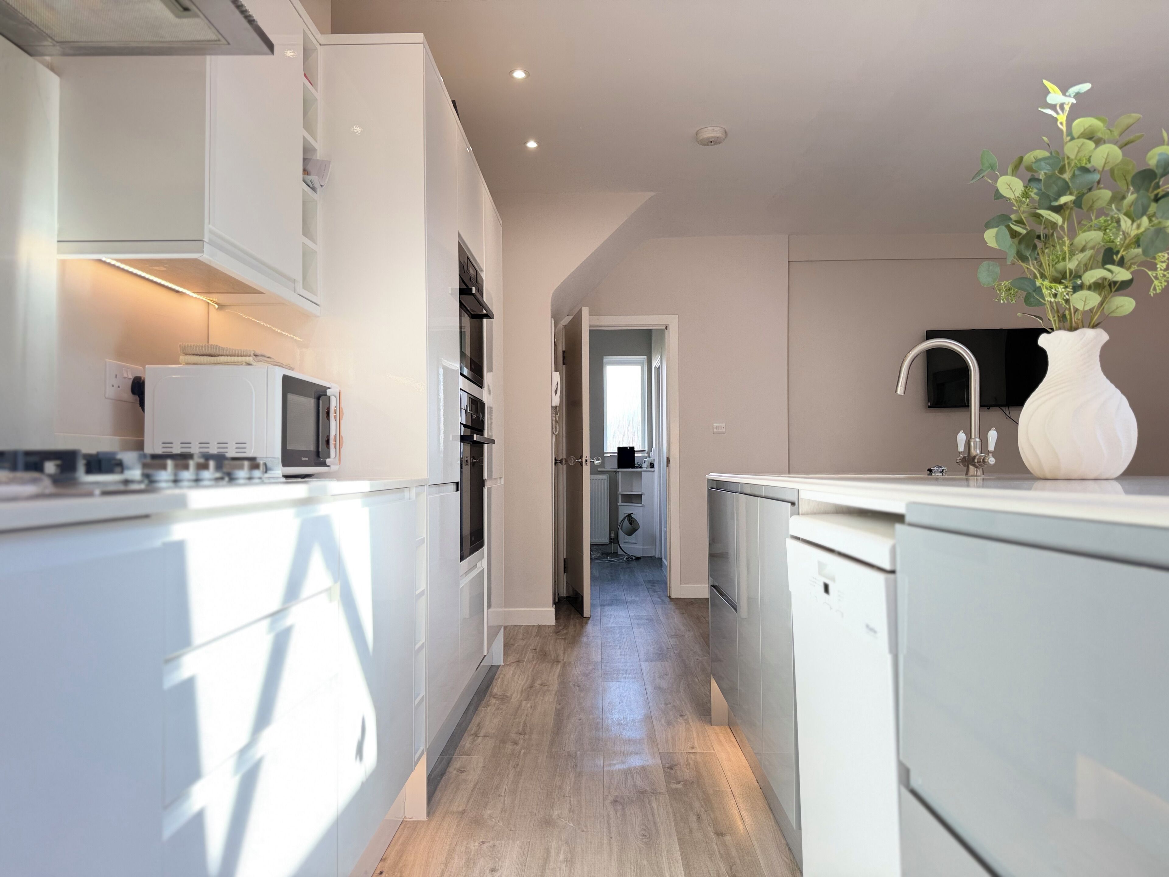 Une cuisine moderne avec des meubles blancs, un four à micro-ondes et un évier.